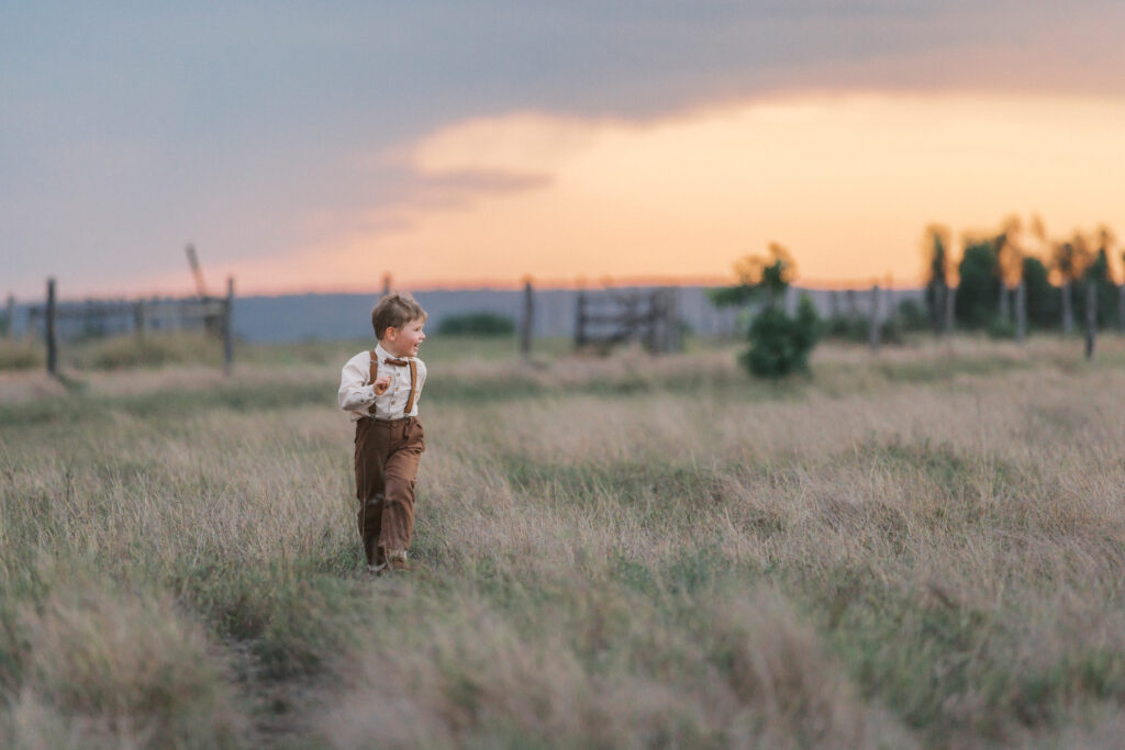 Young boy running through a field during a family photography session