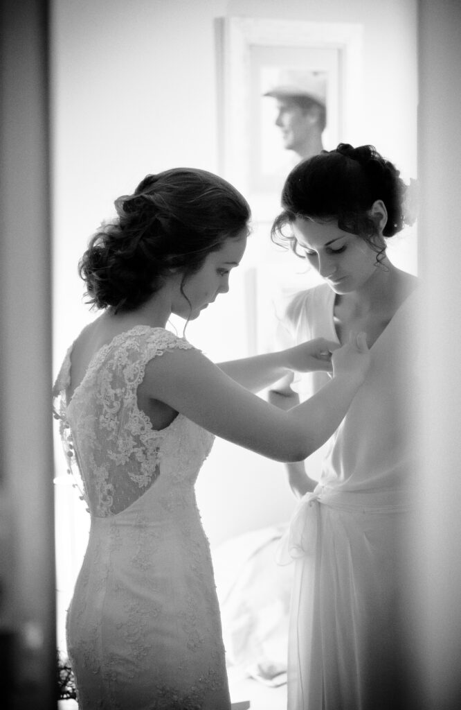 Woman helping the bride adjust her wedding dress
